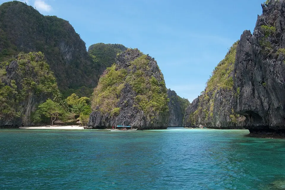 Turquoise lagoon surrounded by dramatic limestone karst formations and lush jungle in El Nido, Palawan, Philippines